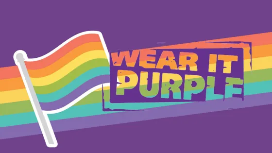 Illustration of a rainbow flag with the text "Wear It Purple" set against a purple background.